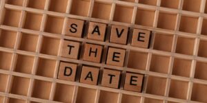 "Save the Date" spelled with wooden tiles for event invitations or reminders.