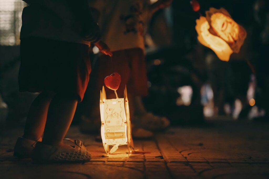 Children holding lit lanterns during a night festival, creating a warm and festive atmosphere.
